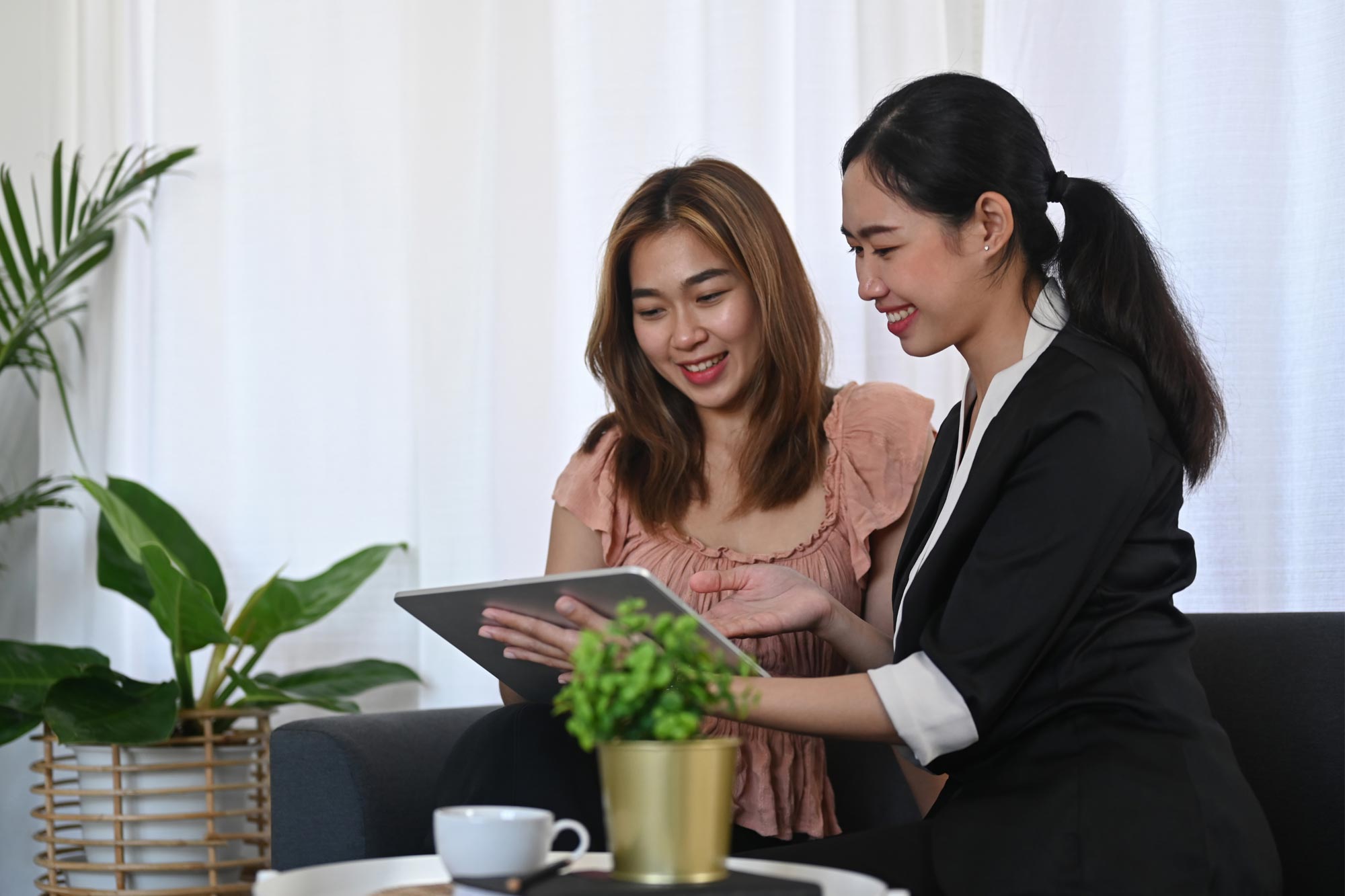 A consultant shows a client results on a tablet while both smile