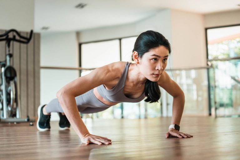 A woman holds a push-up position in a bright fitness studio during a strength session
